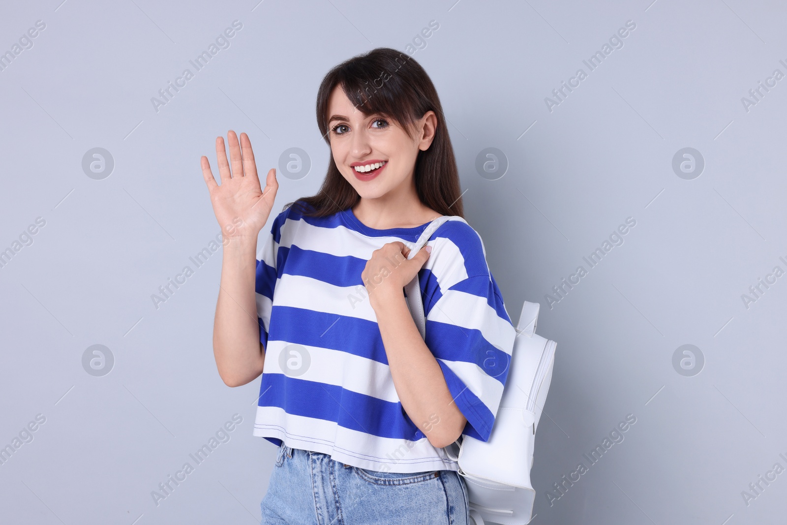 Photo of Happy woman waving on light grey background