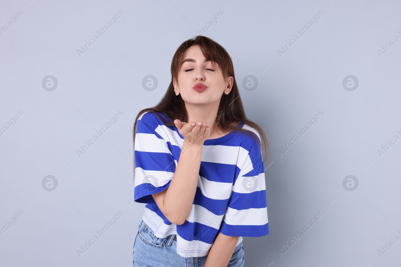 Photo of Beautiful woman blowing kiss on light grey background