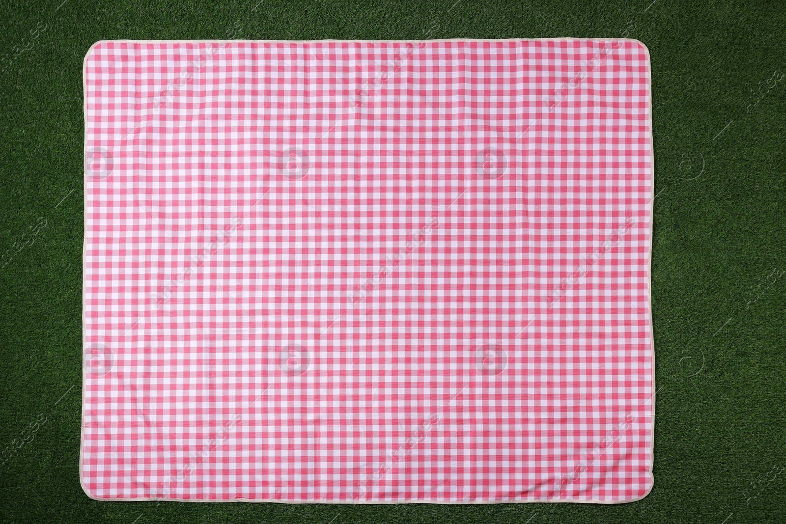 Photo of Checkered picnic tablecloth on green grass, top view