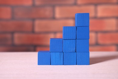 Blank colorful cubes on wooden table against brick wall