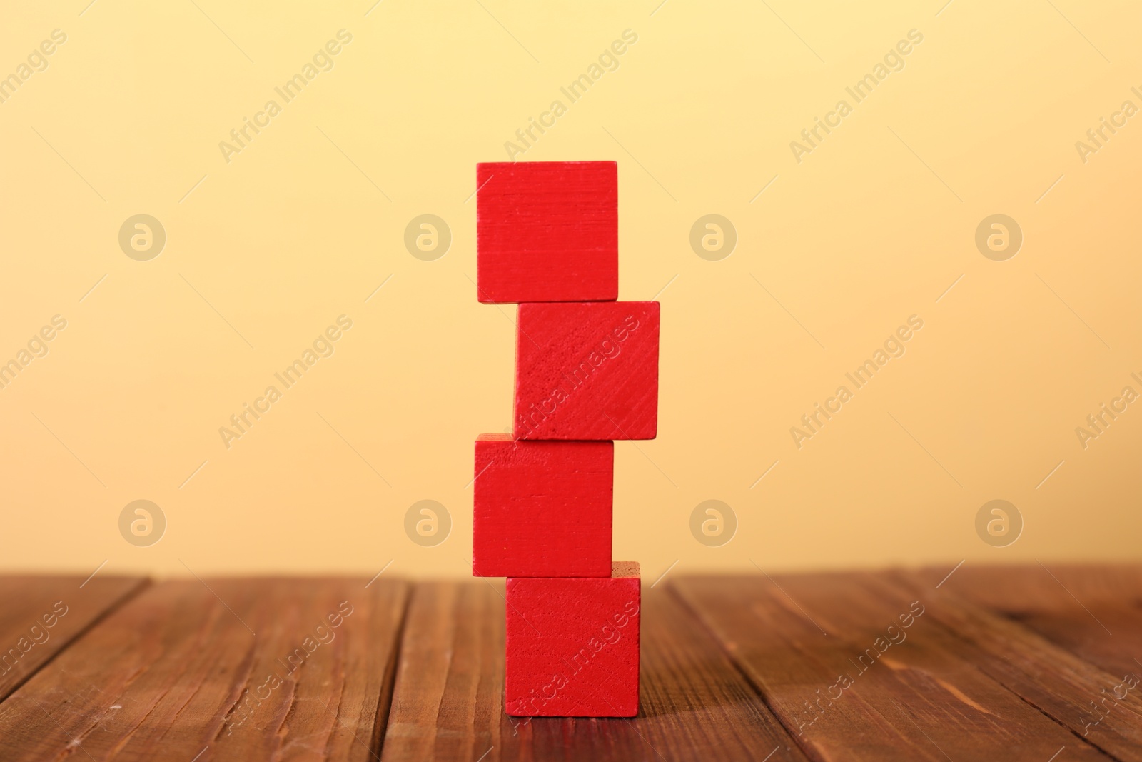 Photo of Blank colorful cubes on wooden table against pale yellow background