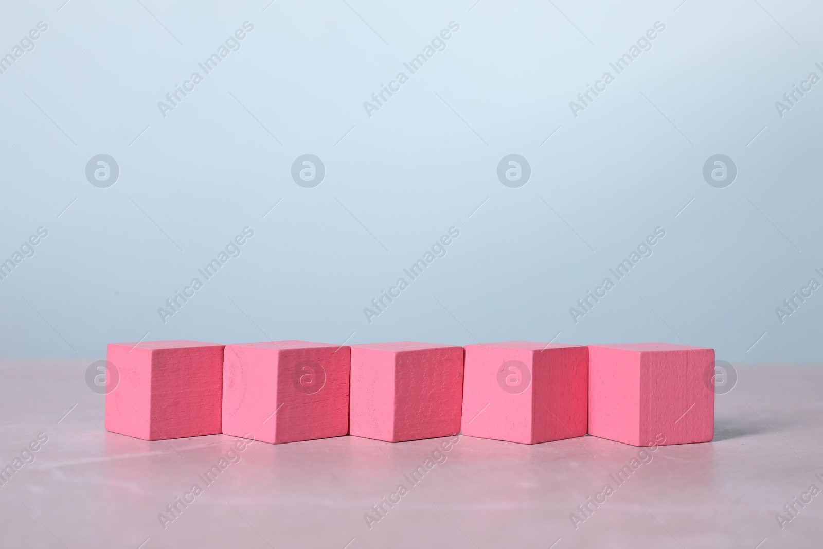 Photo of Blank pink cubes on light grey marble table