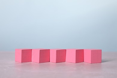 Photo of Blank pink cubes on light grey marble table