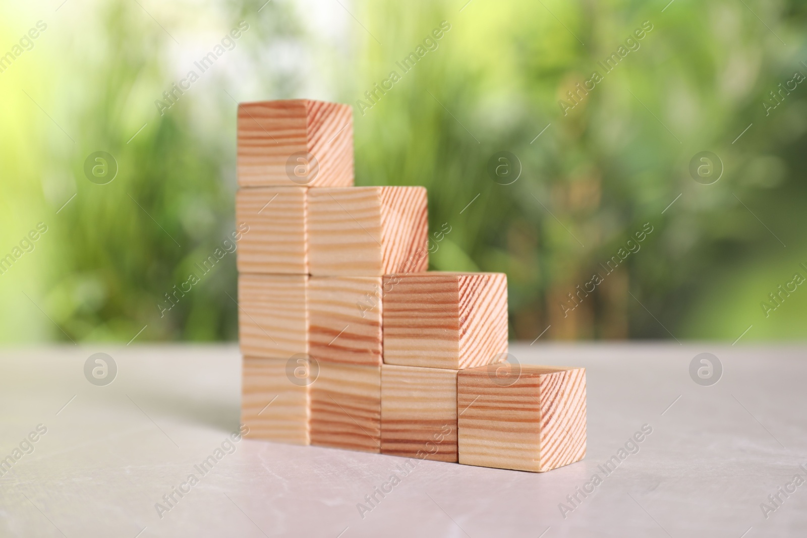 Photo of Many wooden cubes on light grey table outdoors