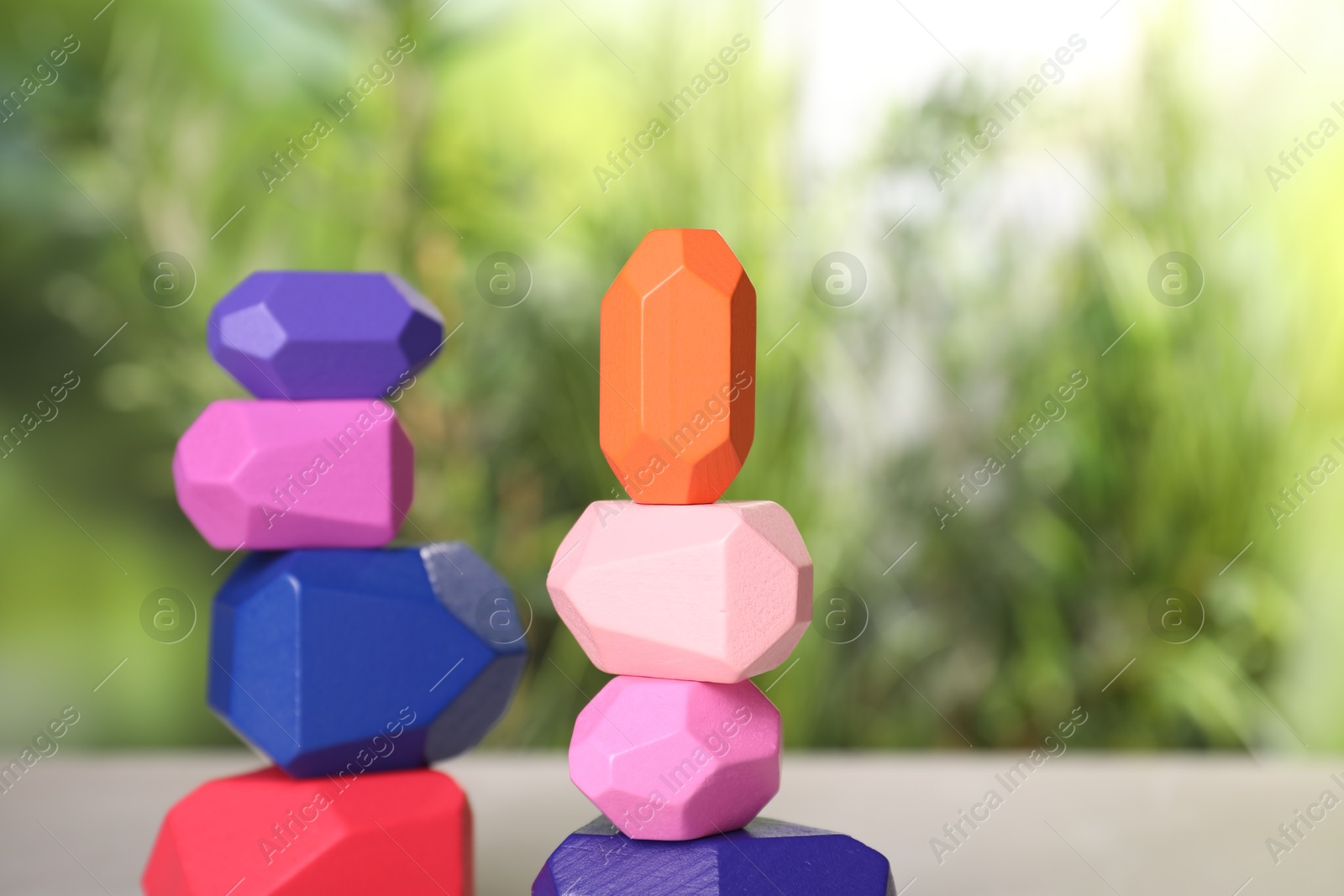 Photo of Many colorful balancing stones against blurred background, closeup. Space for text