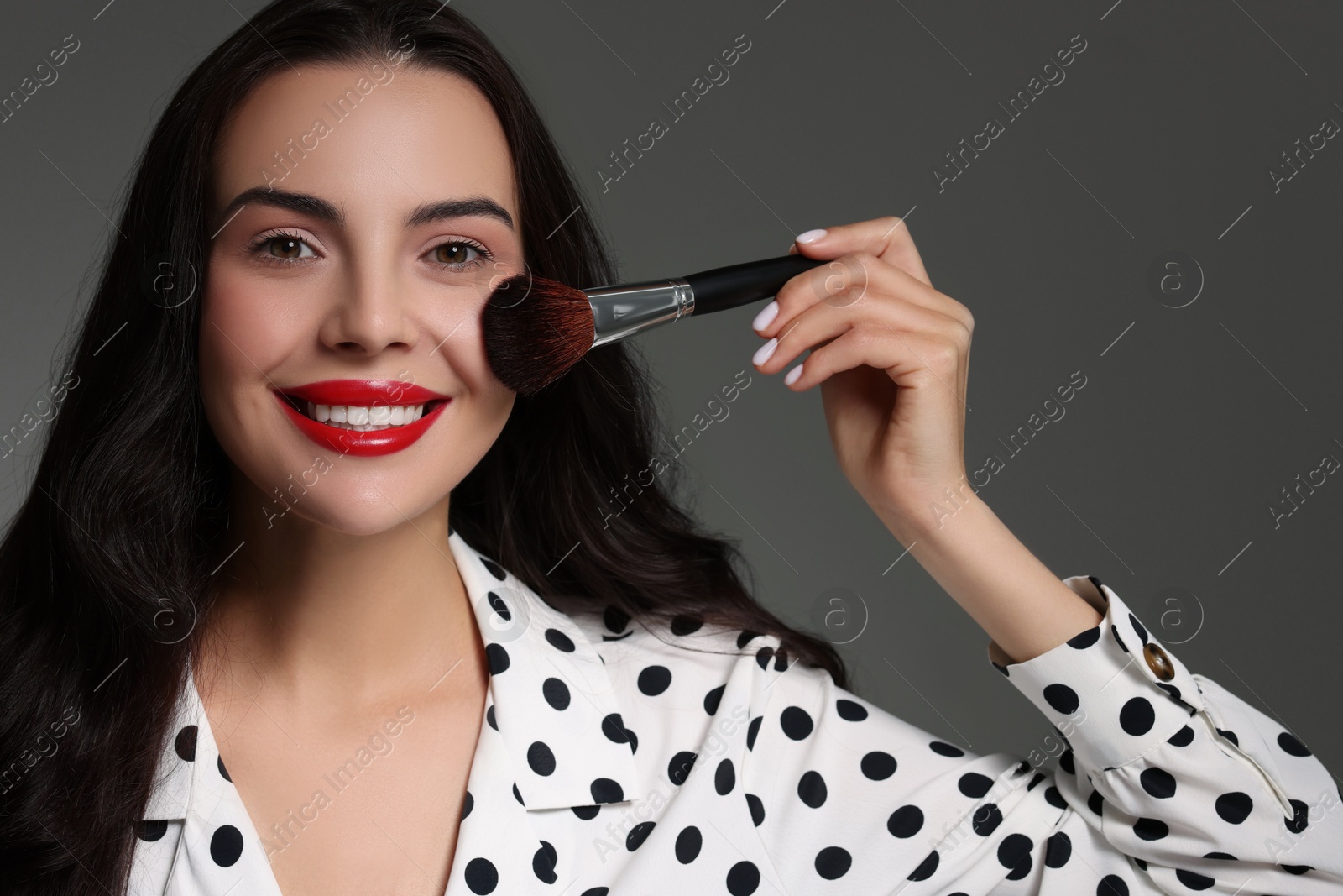 Photo of Beautiful makeup. Smiling woman with brush on grey background