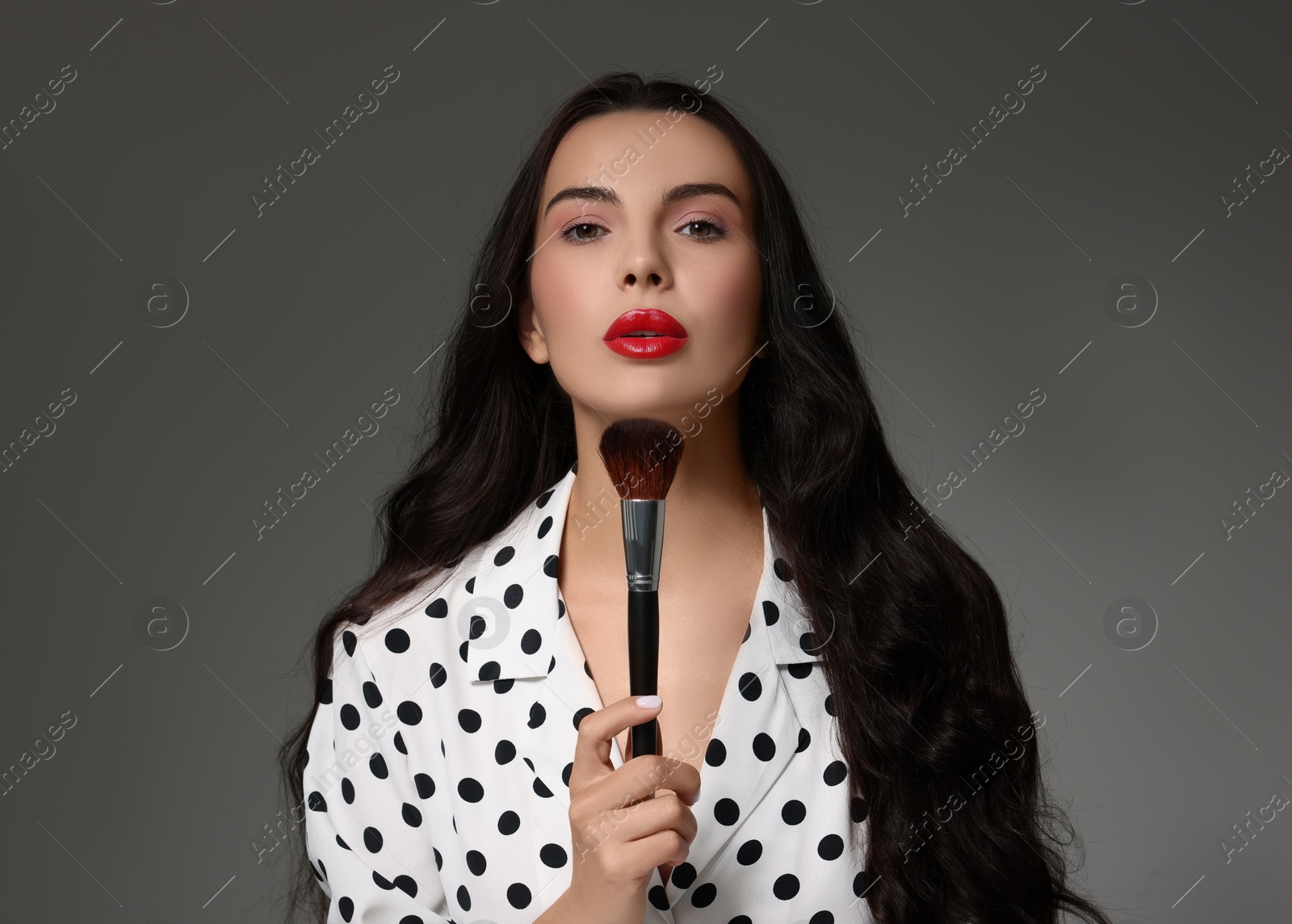 Photo of Beautiful makeup. Attractive woman with brush on grey background