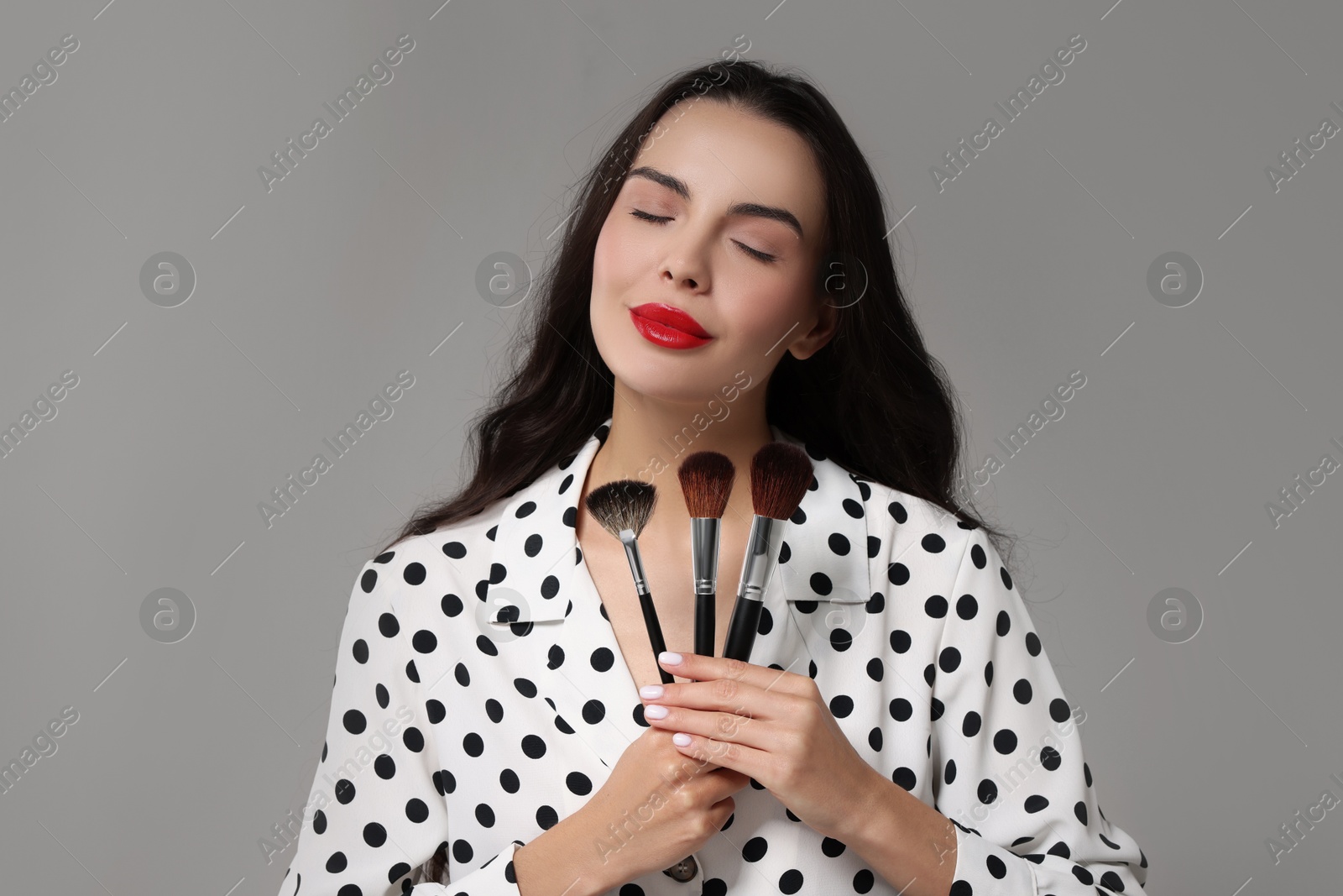 Photo of Beautiful makeup. Attractive woman with brushes on light grey background