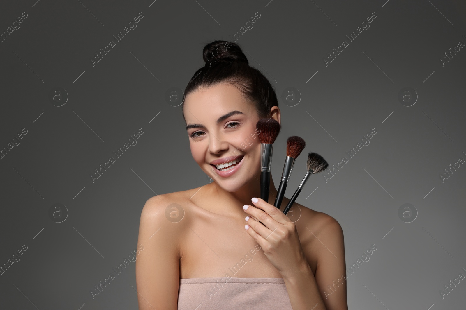 Photo of Beautiful makeup. Smiling woman with brushes on grey background