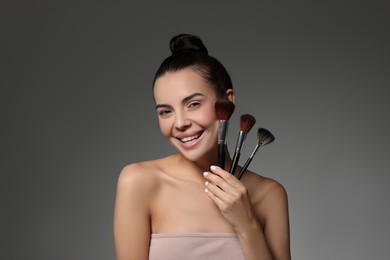 Beautiful makeup. Smiling woman with brushes on grey background