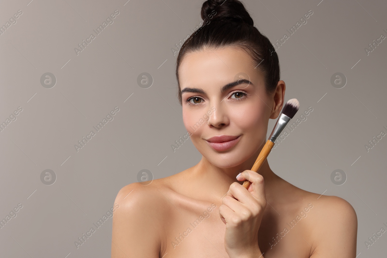 Photo of Beautiful makeup. Attractive woman with brush on grey background, space for text