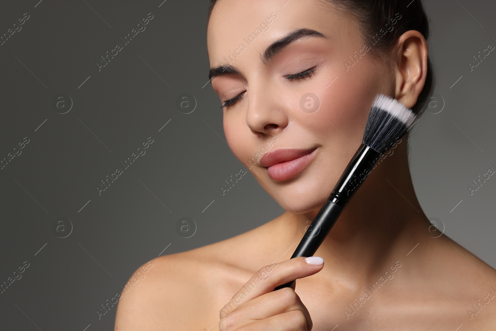 Photo of Beautiful woman with makeup brush on grey background. Space for text