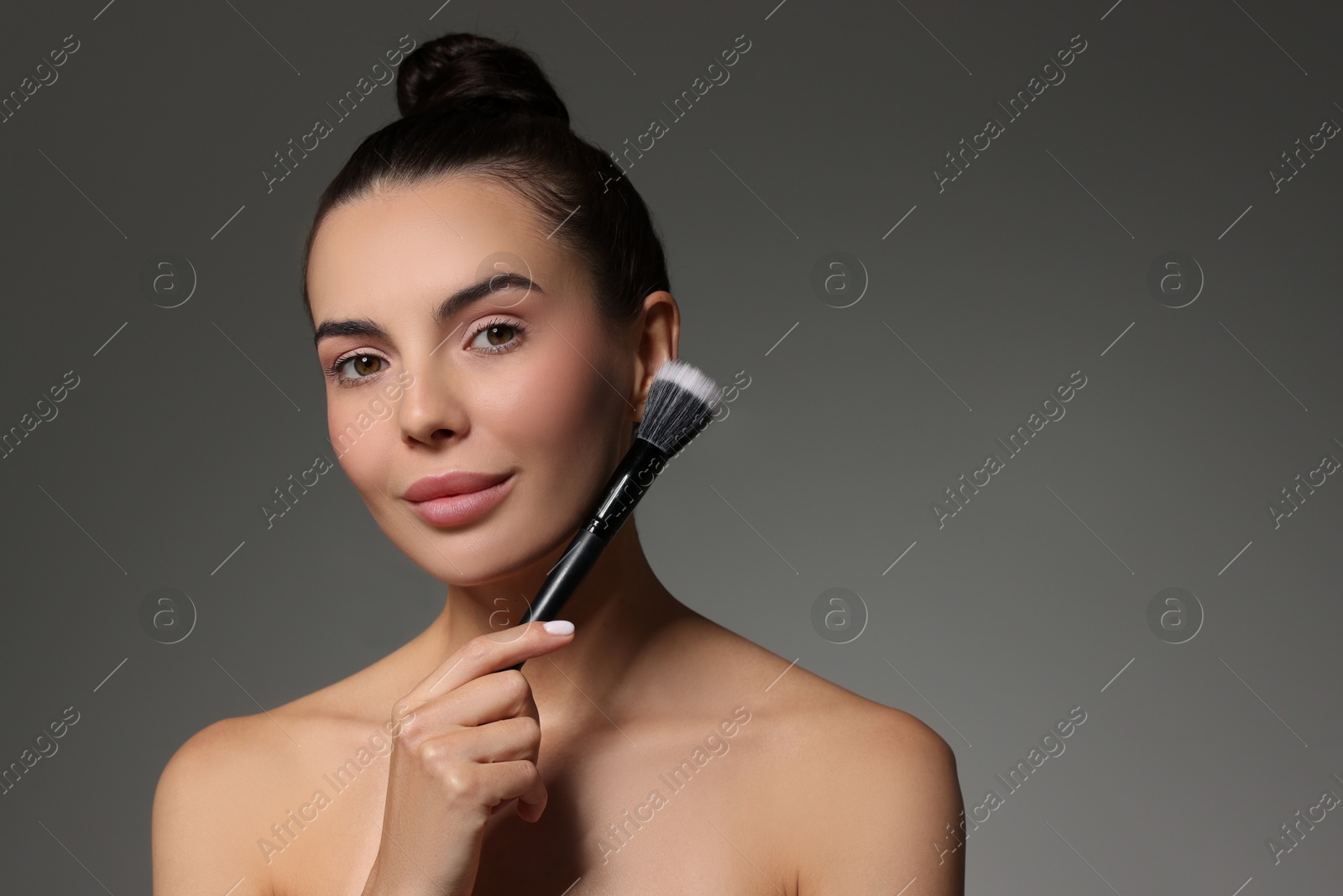 Photo of Beautiful woman with makeup brush on grey background. Space for text