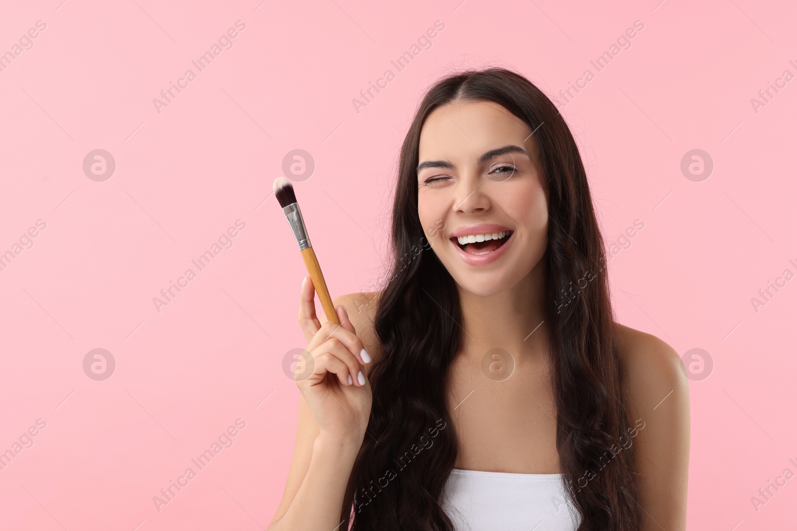 Photo of Beautiful makeup. Smiling woman with brush on pink background, space for text