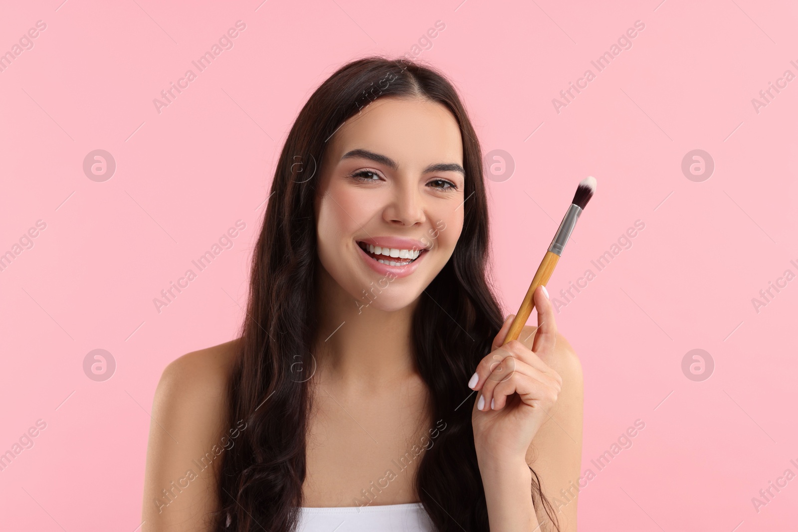 Photo of Beautiful makeup. Smiling woman with brush on pink background