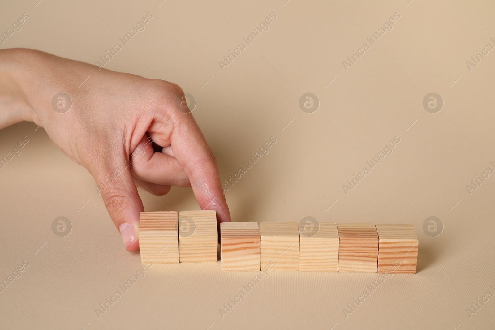 Photo of Woman with wooden cubes on beige background, closeup