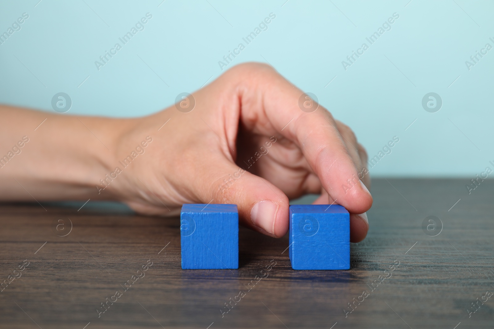 Photo of Woman with blue cubes at wooden table, closeup