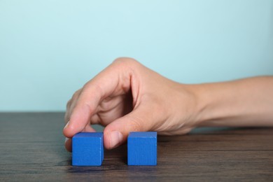 Photo of Woman with blue cubes at wooden table, closeup