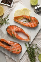 Photo of Tasty grilled salmon steaks, lemon, lime and spices on table, flat lay