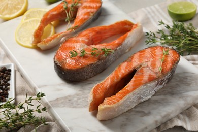 Photo of Tasty grilled salmon steaks, lemon and thyme on table, closeup