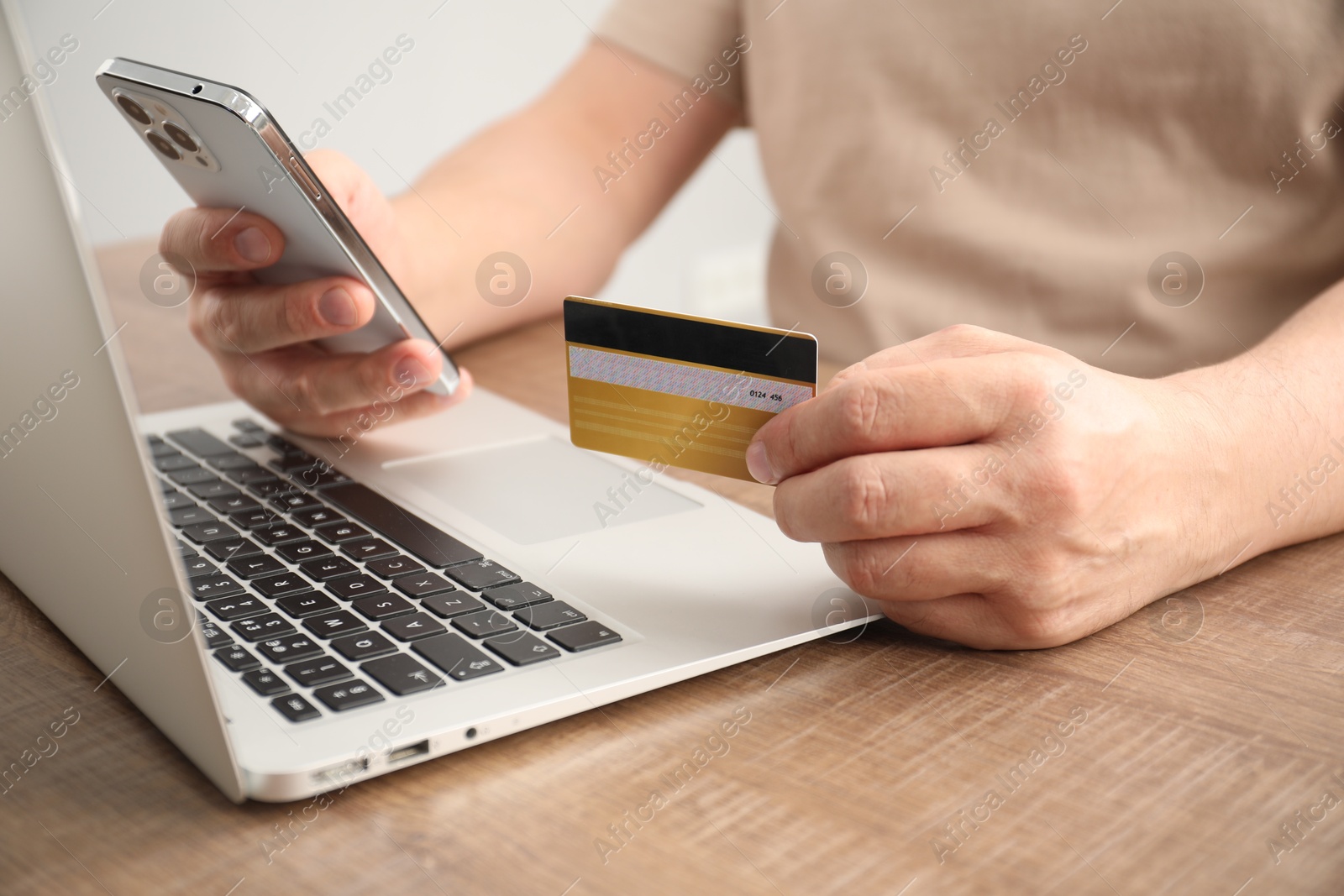 Photo of Man with credit card and smartphone at wooden table indoors, closeup