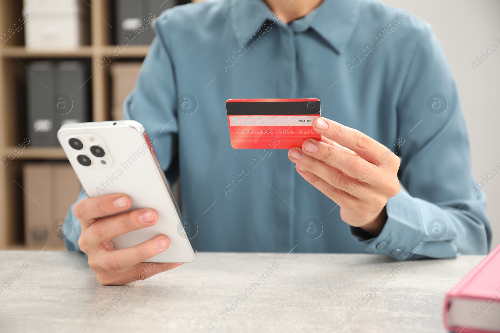 Photo of Man with credit card and smartphone at light table indoors, closeup