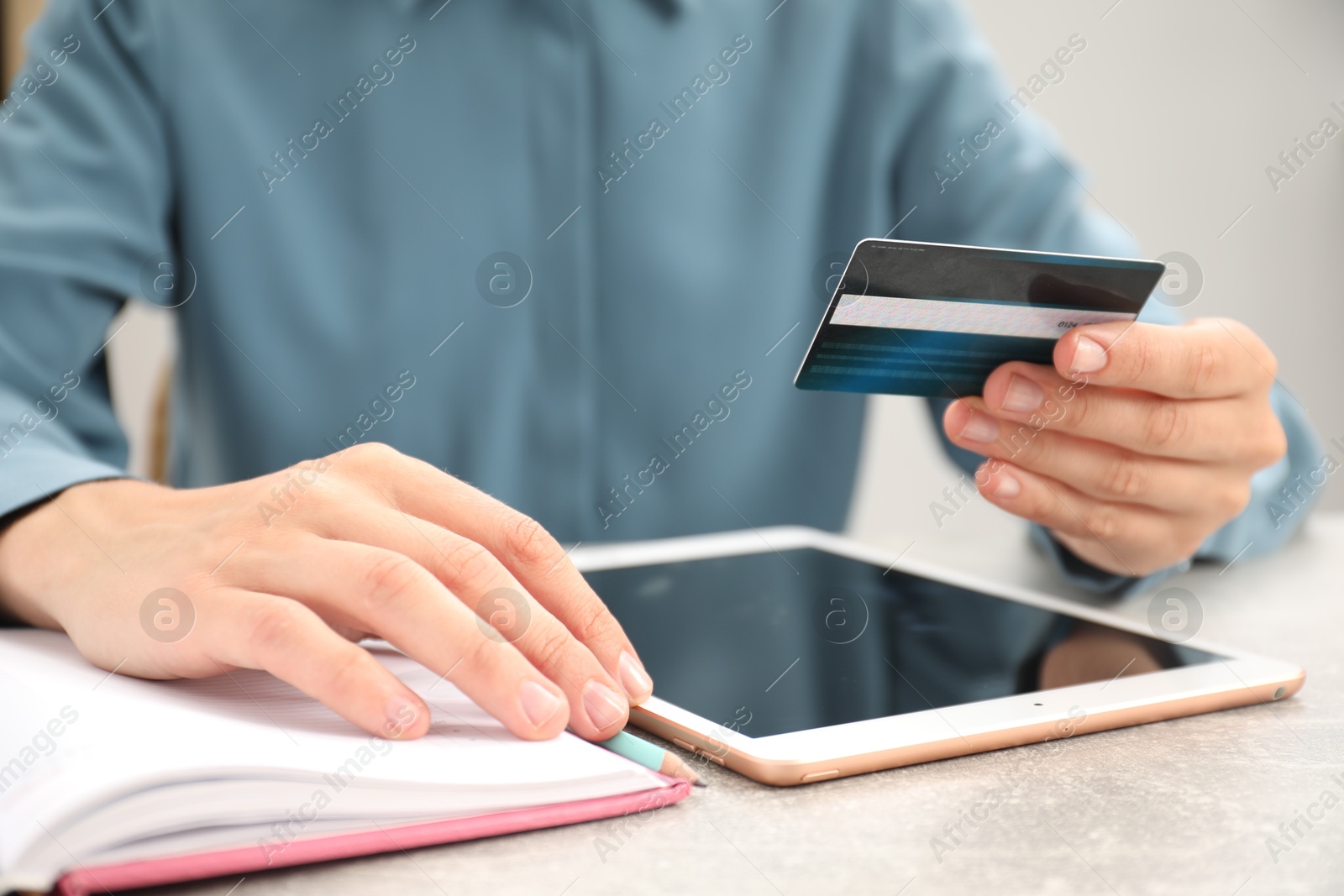 Photo of Man with credit card using tablet at light table indoors, closeup