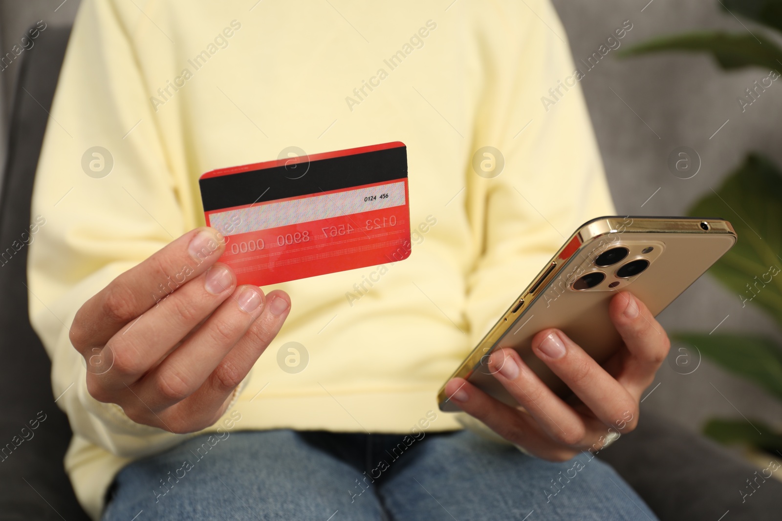 Photo of Woman with credit card and smartphone indoors, closeup