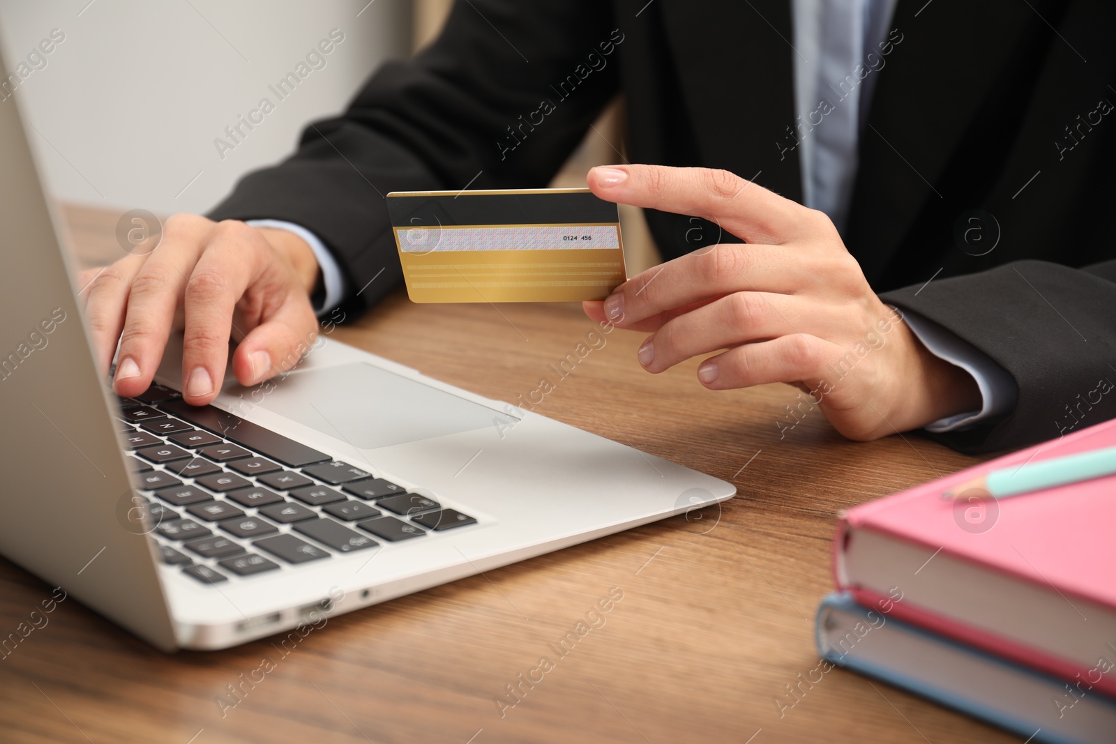 Photo of Man with credit card using laptop at wooden table indoors, closeup