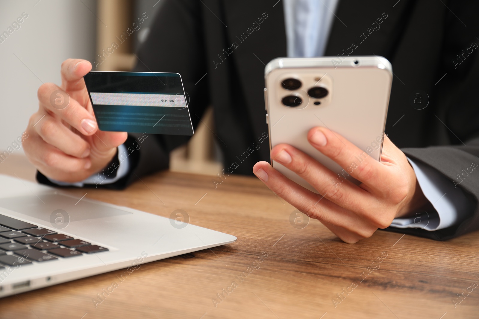 Photo of Man with credit card and smartphone at wooden table indoors, closeup