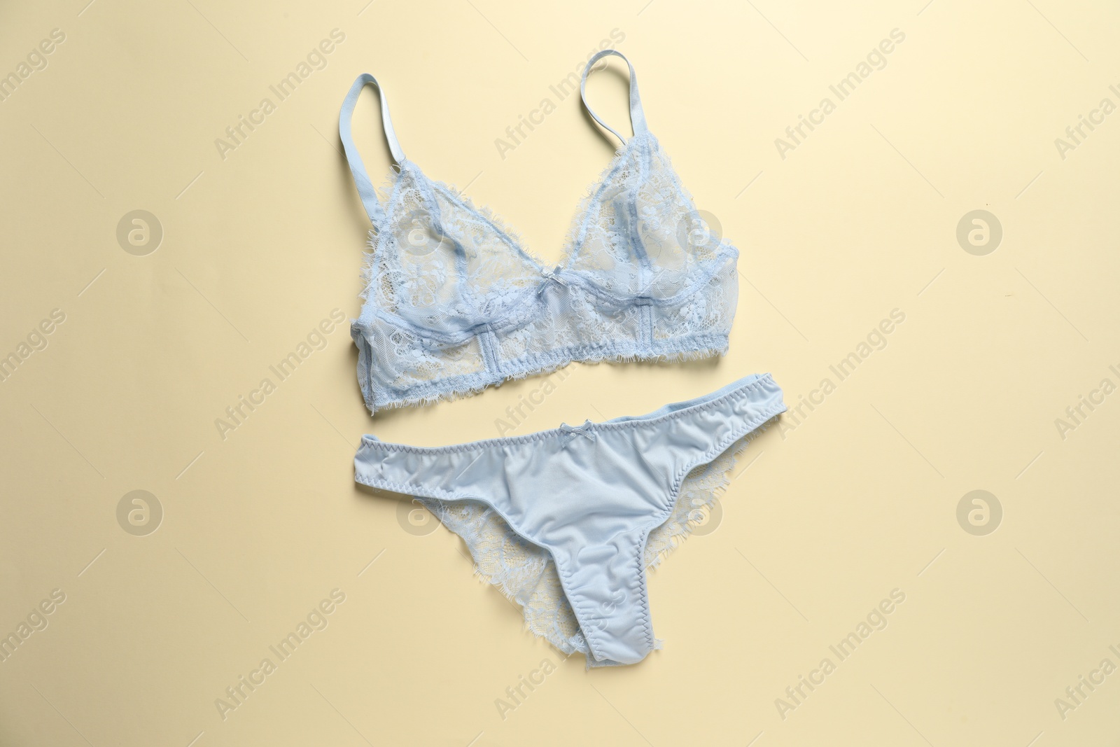 Photo of Elegant light blue lace women's underwear on beige background, top view