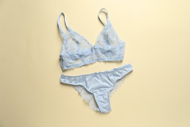 Photo of Elegant light blue lace women's underwear on beige background, top view