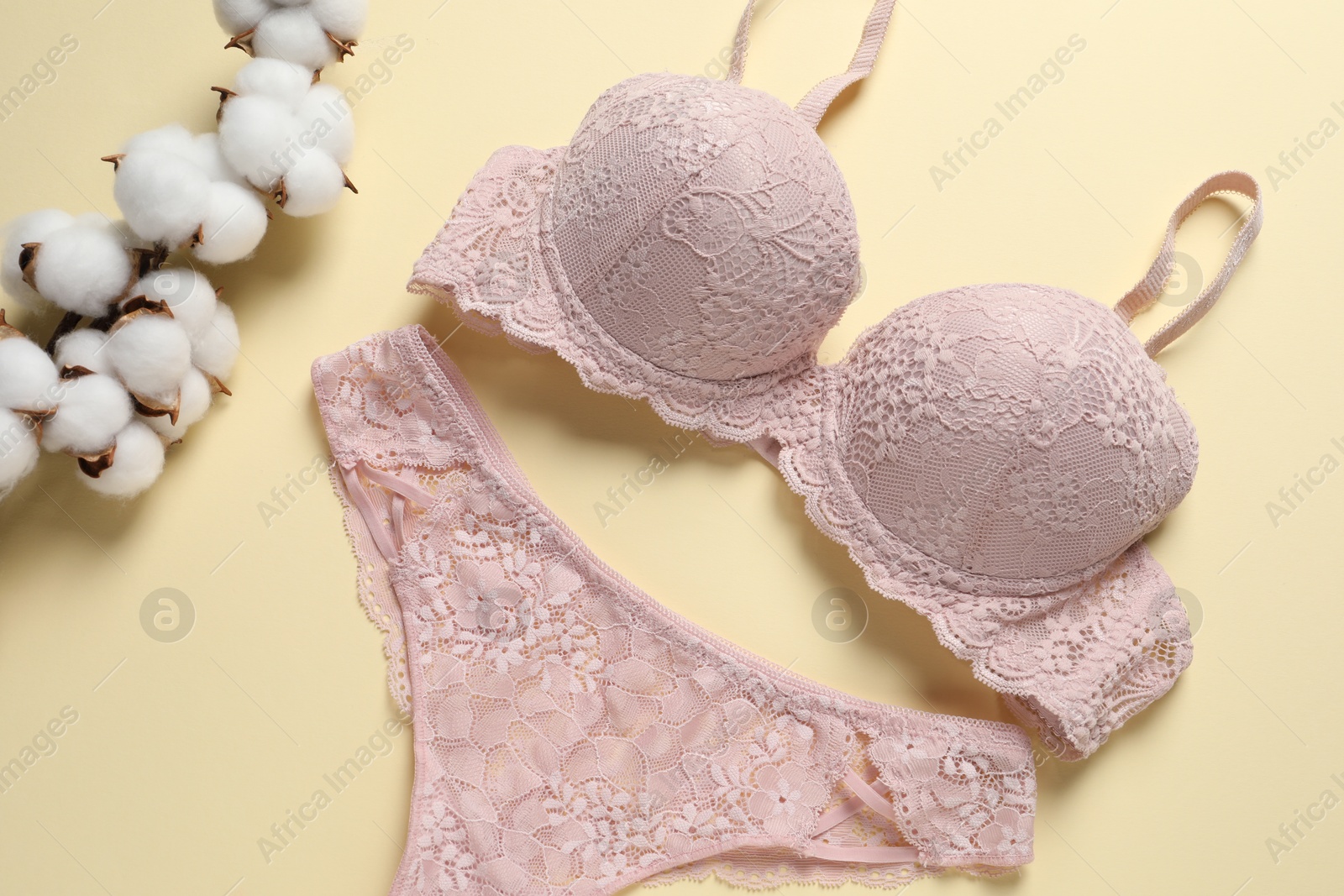 Photo of Elegant pink lace women's underwear and cotton flowers on beige background, top view