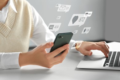 Image of Content manager. Woman working on laptop and smartphone indoors, closeup. Likes, followers, e-mails, messages and adding to favorite notifications over device