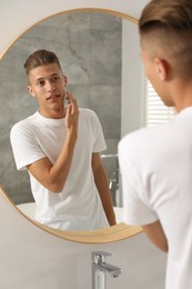 Photo of Handsome man looking at mirror in bathroom