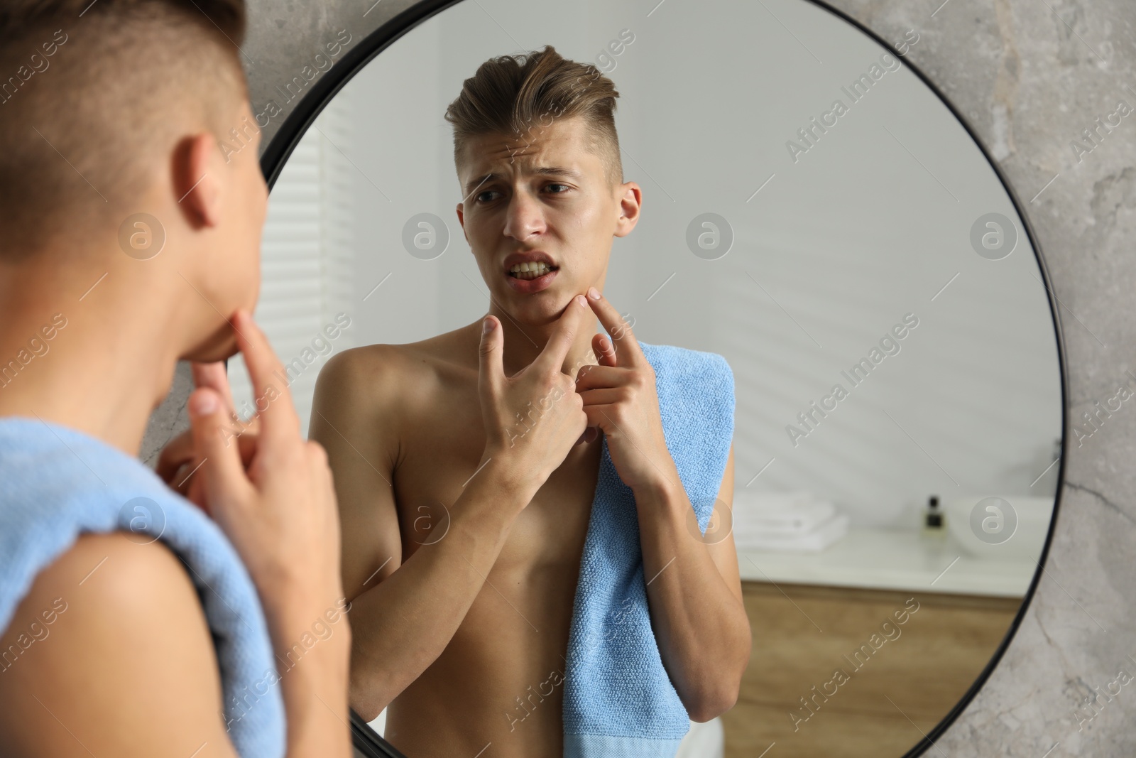 Photo of Man with towel touching his face near mirror in bathroom