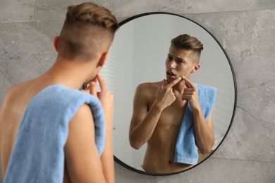 Photo of Man with towel touching his face near mirror in bathroom