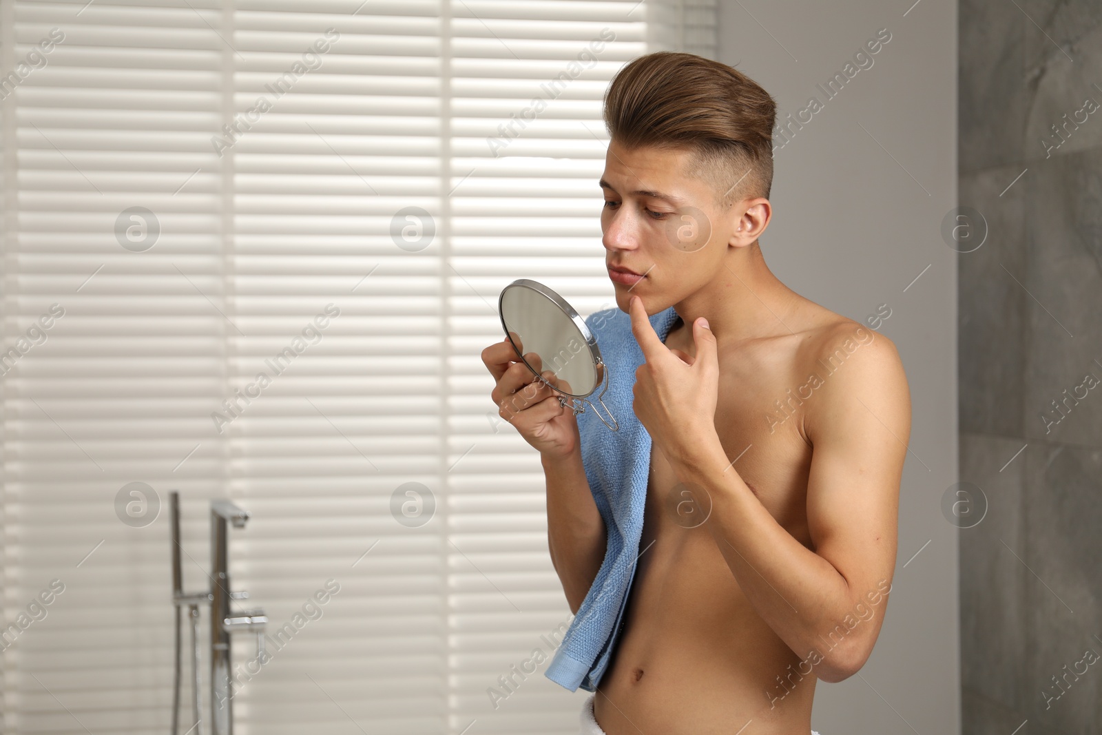 Photo of Man with mirror touching his face in bathroom, space for text