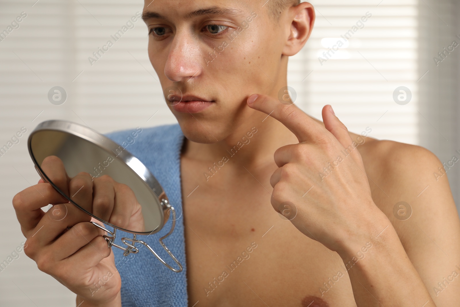 Photo of Man with mirror touching his face in bathroom