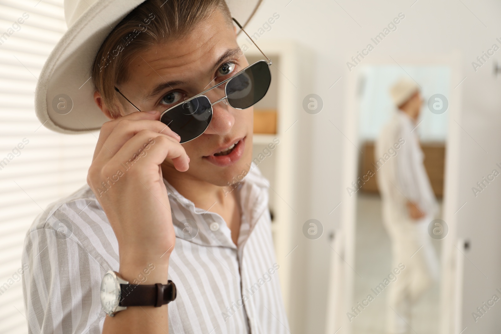 Photo of Handsome man in hat and glasses indoors, space for text