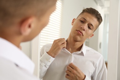 Photo of Handsome man in shirt near mirror indoors