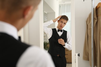 Photo of Handsome man in shirt looking at mirror indoors