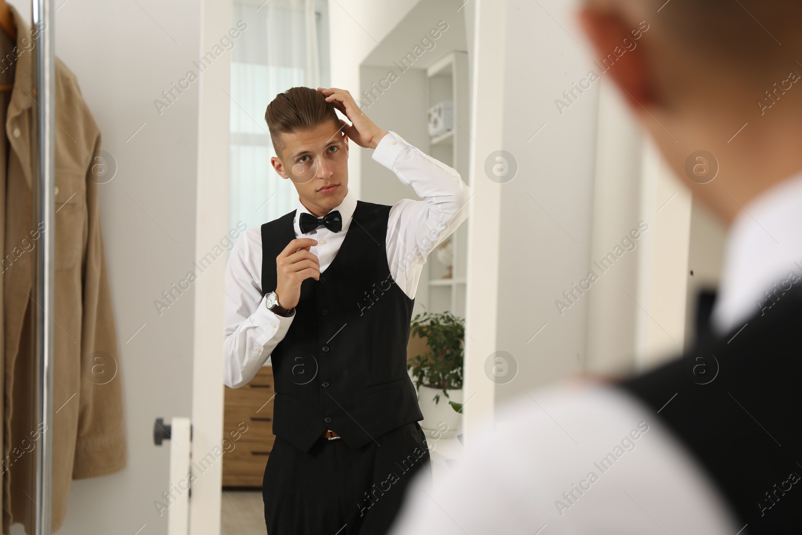 Photo of Handsome man in shirt looking at mirror indoors