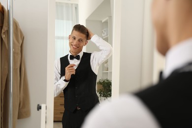Photo of Handsome man in shirt looking at mirror indoors