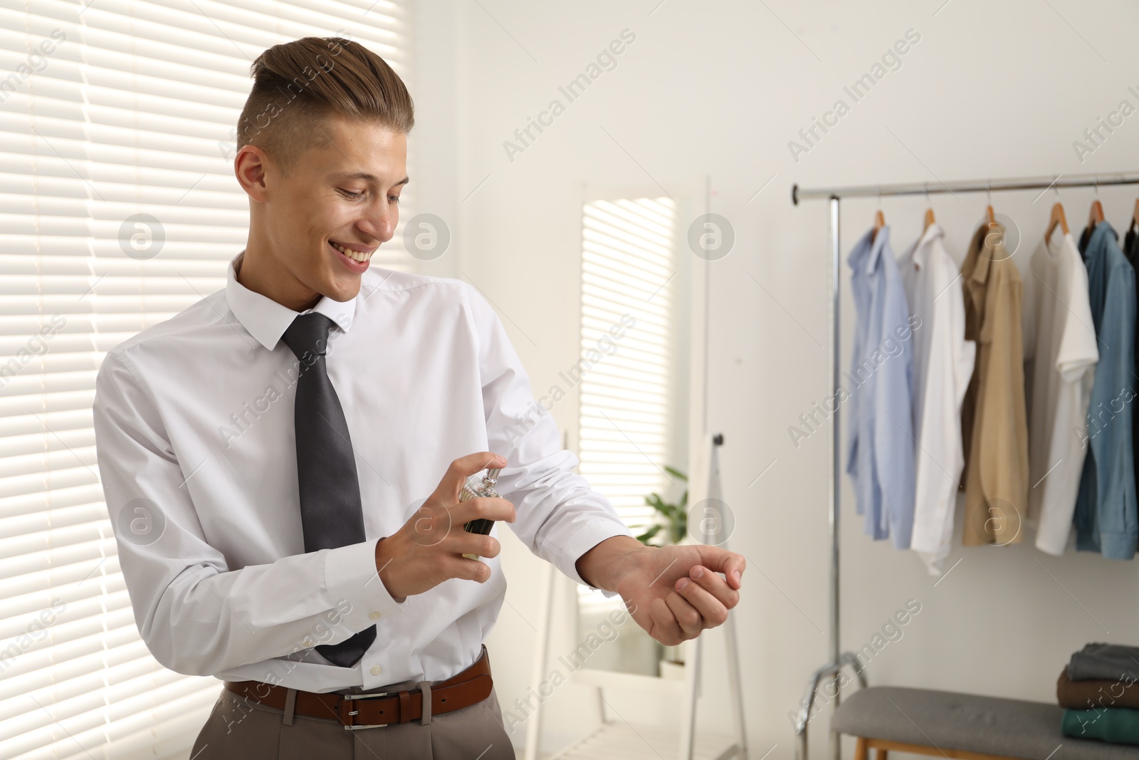 Photo of Happy man spraying luxury perfume at home