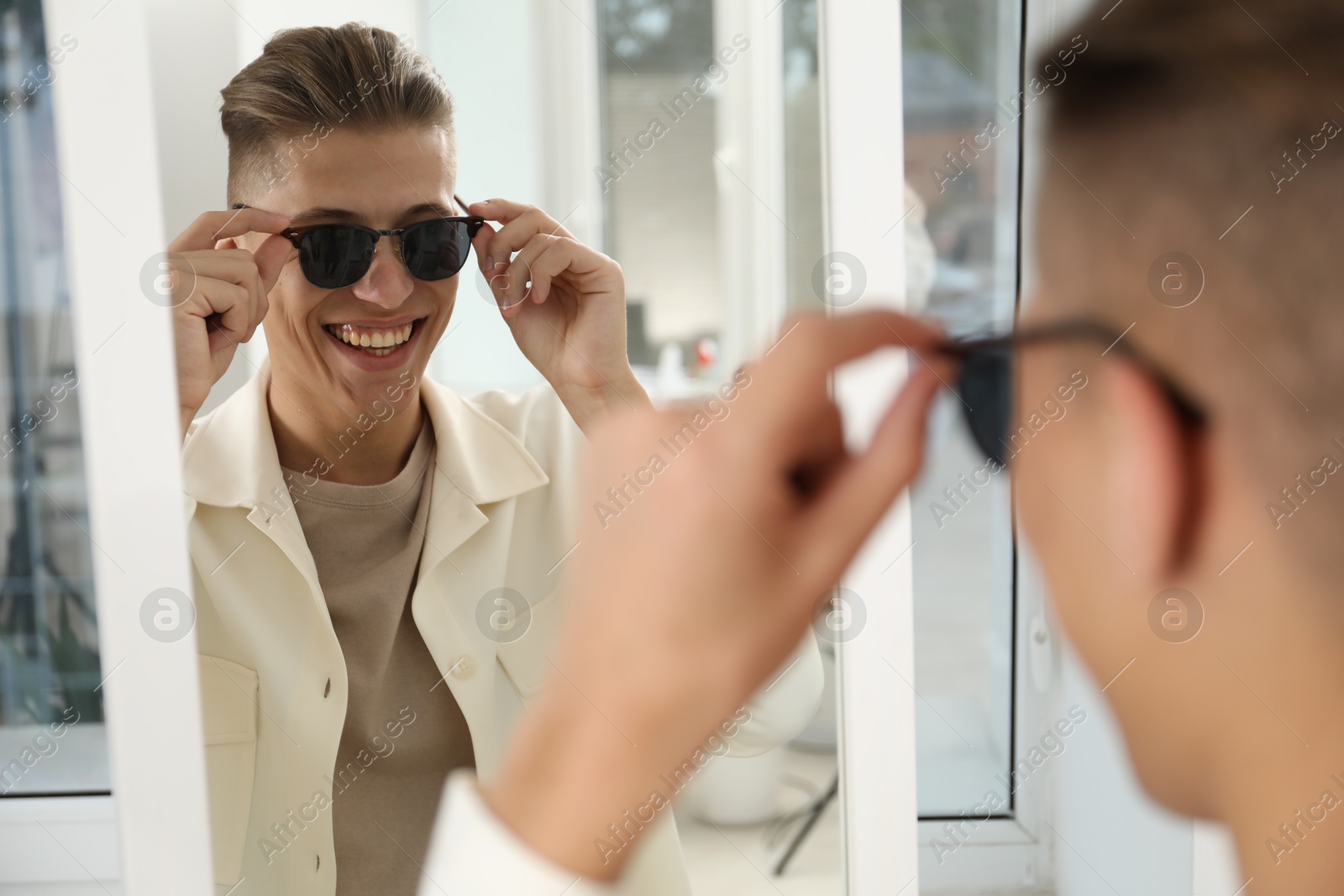 Photo of Handsome man in glasses looking at mirror indoors