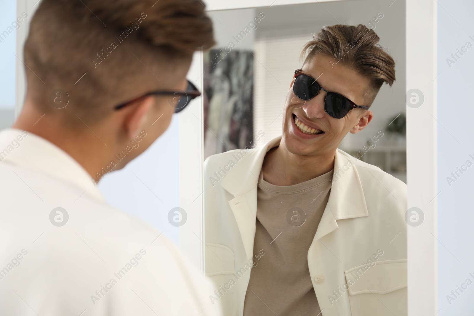 Photo of Handsome man in glasses looking at mirror indoors