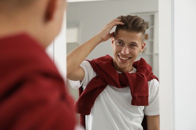 Photo of Handsome man looking at mirror at home