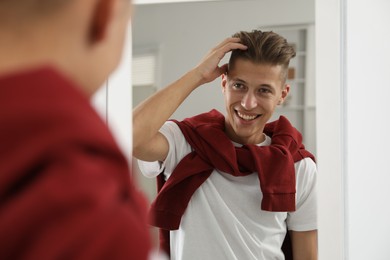 Handsome man looking at mirror at home