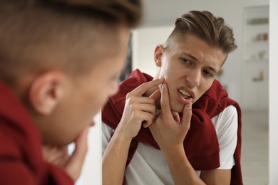 Man touching his face near mirror indoors